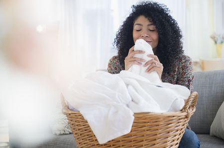 mixed-race-woman-smelling-clean-towels-in-laundry-557475315-598fae6f6f53ba00104a6275 Cuidados com Toalha, quais devemos tomar? Toalha para Casa
